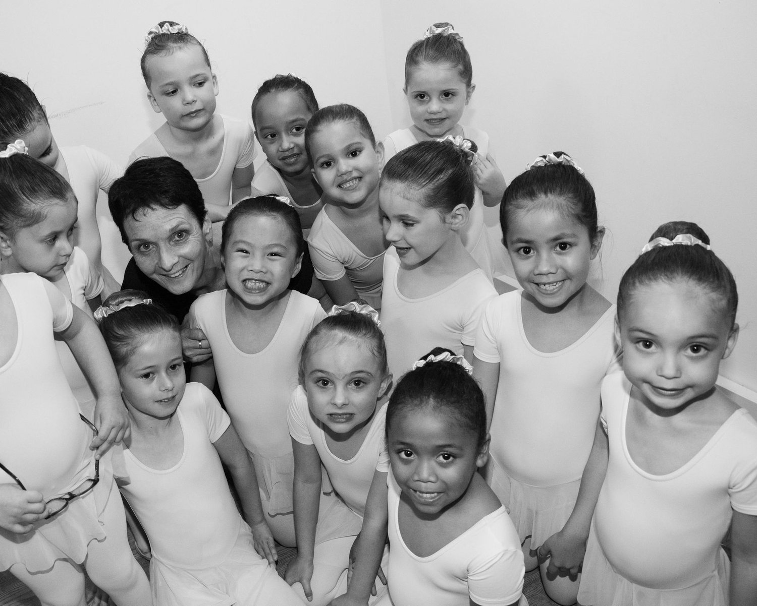 Groupe de petites danseuses souriantes en coulisses, en noir et blanc