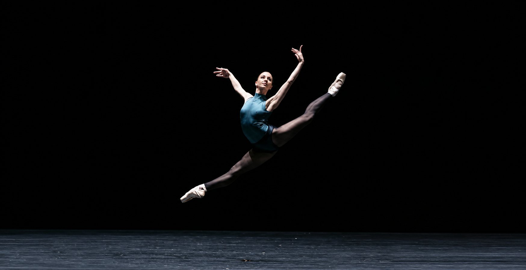 Danseuse classique en pleine arabesque temps levé sur scène