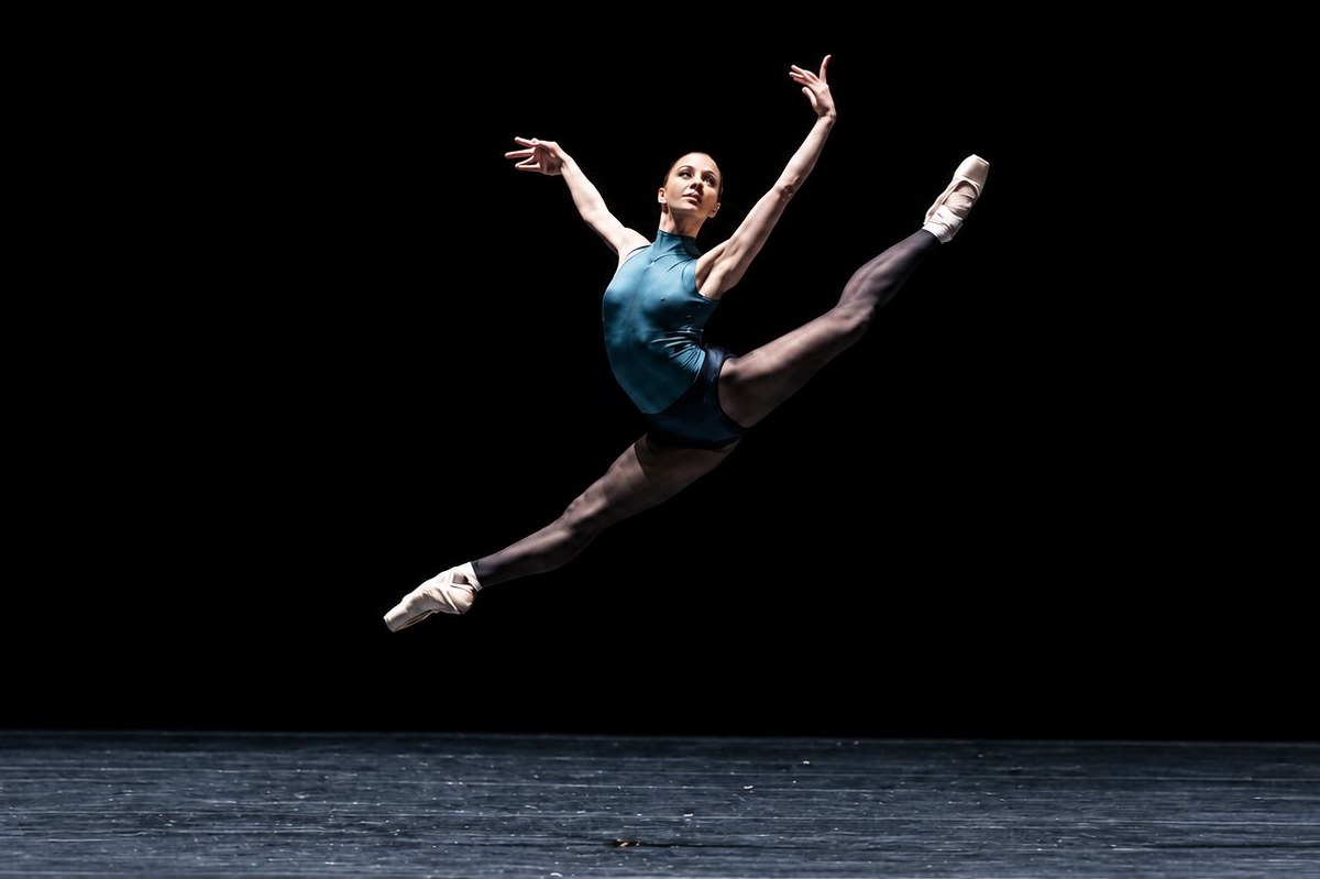 Danseuse classique en pleine arabesque temps levé sur scène