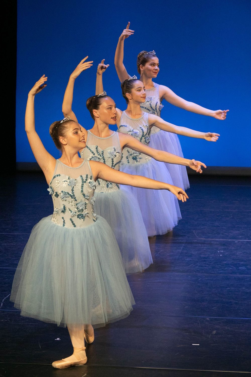 Danseuses bras levés en costumes pastel sur scène